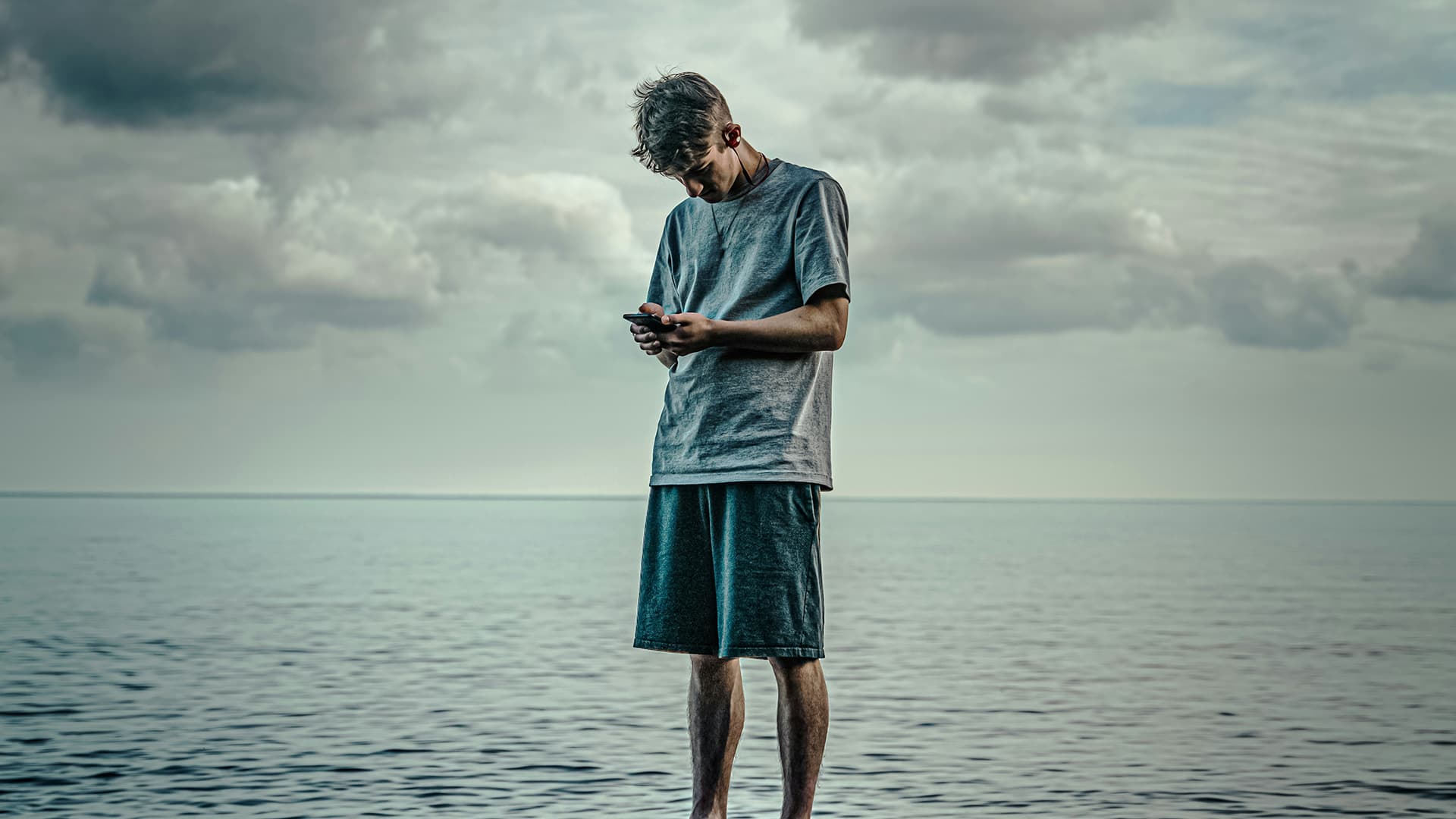 A man looking at his phone while standing in a large body of water